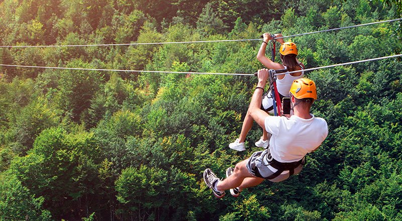 Zipline is an exciting adventure activity. Man and woman hanging on a rope-way. Tourists ride on the Zipline through the canyon of the Tara River Montenegro. Couple in helmets is riding on a cable car