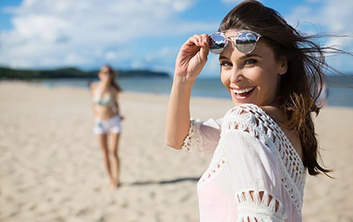 Happy beautiful woman standing on beach with friend laughing